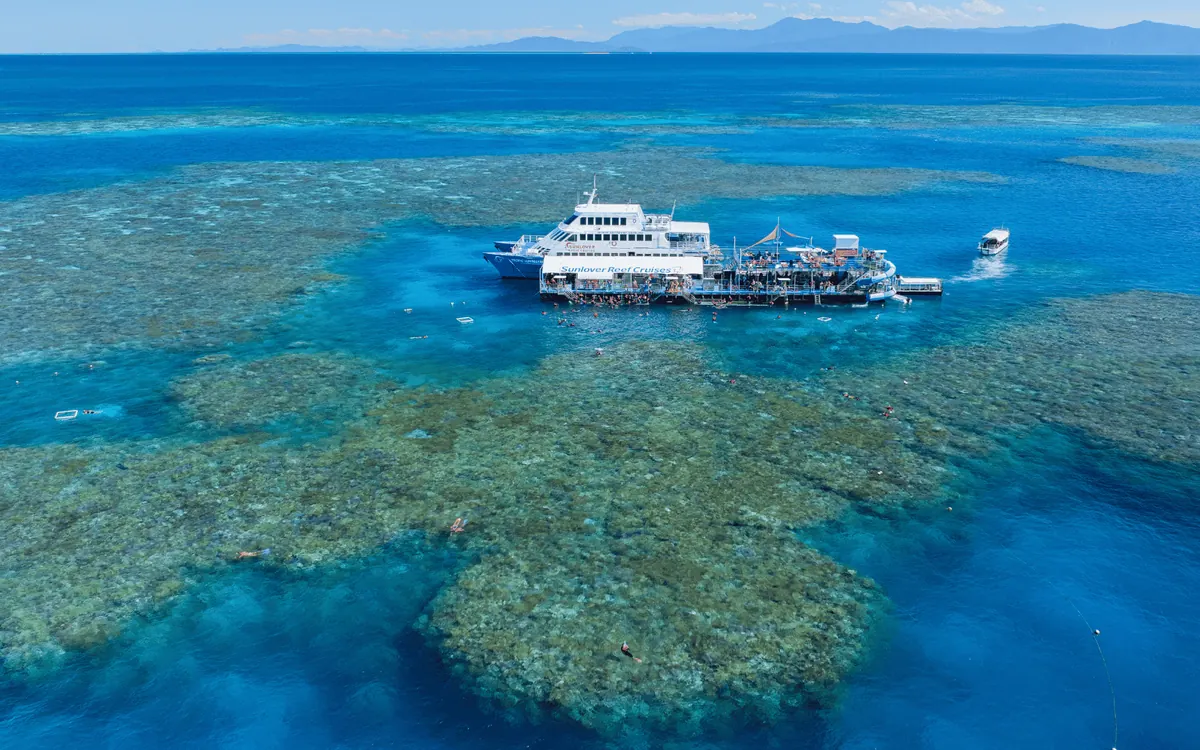 A crew member briefing snorkellers and divers on the rear deck of a reef boat before they enter the water